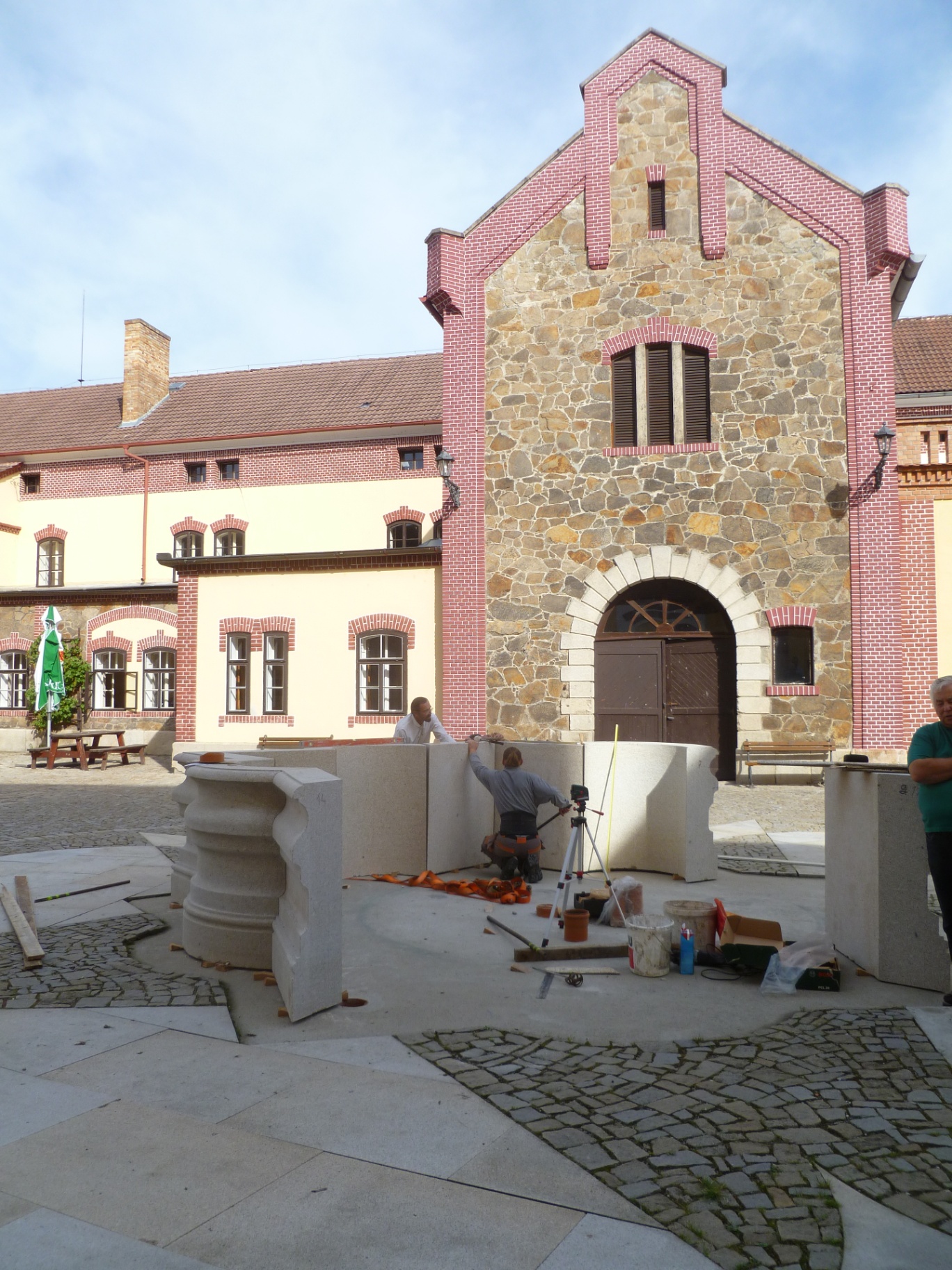 Pivovar Třeboň — osazování dílů kašny před stodolou