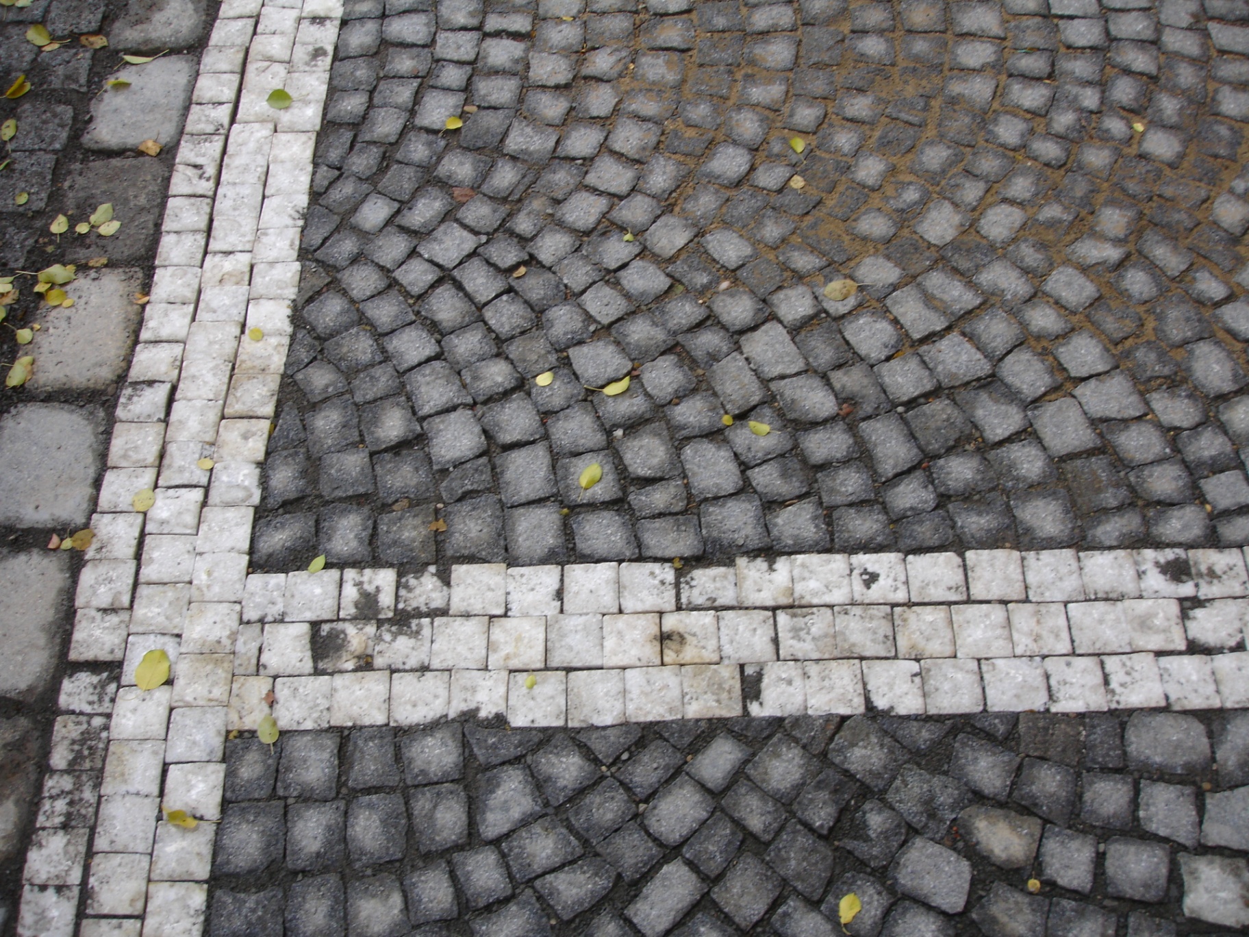 Detail žulové mozaikové dlažby s bílými liniemi